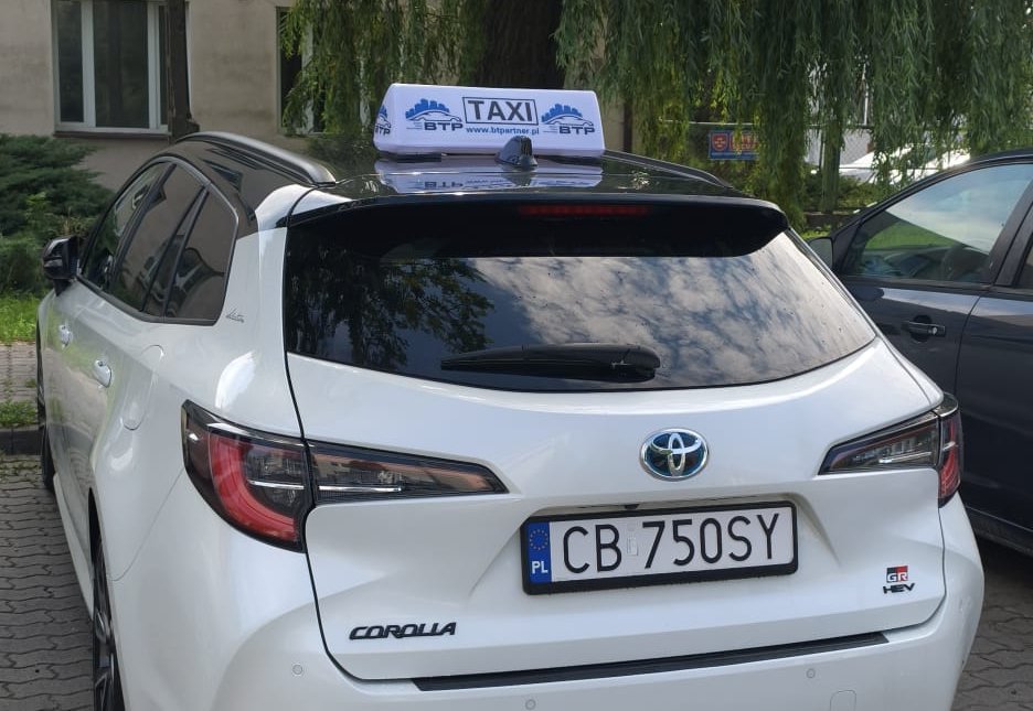 Biała Toyota Corolla z lampą BTP TAXI